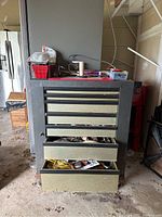 Front view of metal tool chest showing all drawers with some open and contents inside, set in garage environment.
