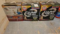 Three Arm & Hammer Clump & Seal Multi-Cat kitty litter boxes on floor, one opened, two unopened.