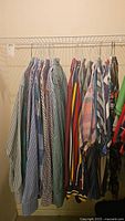 Long view of 11 men's long sleeve button down shirts hanging on wire rack showing variety of colors and patterns.