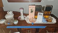 Overall collection of porcelain trinket boxes, ring holder, tray, and perfume bottles on wooden surface.