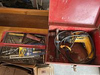 Yellow DeWalt DW505 corded hammer drill with attached power cord and side handle inside a red steel toolbox.