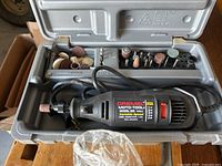 Open plastic case showing Dremel Moto-Tool Model 395 with bits in labeled slots and bit holder compartment.