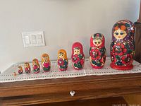 Full set of 9 nesting dolls arranged in size order from smallest to largest on wooden surface