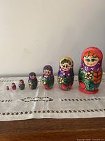 Full set of 6 traditional nesting dolls arranged in descending size order on a white cloth.