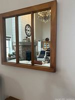 Front view of the three-panel mirror mounted on a wall reflecting living room interior.