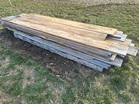 Side-angle view of stacked rough sawn pine boards on grass