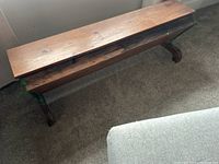 Full view of wooden plank bench with cast iron ends and hinged top closed