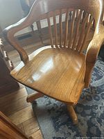 Front view of vintage wooden desk chair, showing curved backrest, armrests, and seat