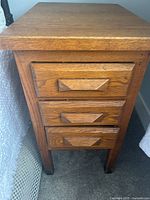 Front view showing three vertically stacked drawers with solid oak wood drawer pulls.