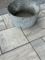 Top-down image showing round metal wash bucket with interior ribbed circular bottom pattern and handles on the sides