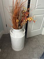 Full view of white painted milk can with dried floral arrangement inside