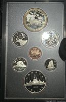 Photo showing all seven coins in original holder, featuring denominations from 1 cent to 2 dollars, with detailed engravings.
