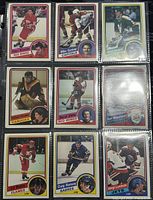 Photo showing 9 1984-5 O-Pee-Chee NHL player trading cards in protective plastic sleeves, featuring players from various NHL teams.