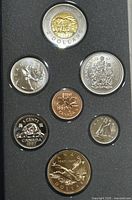 Top view of 7 Canadian specimen coins from 1997 in display, showing front sides including various designs such as the polar bear on 2 dollars coin and others.