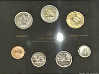 Full set of 7 Canadian coins from 2005 in specimen condition displayed in black frame with gold lettering. Coins include 1 cent, 5 cents, 10 cents, 25 cents, 50 cents, 1 dollar, and 2 dollars.