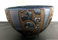 Side view of the large pottery bowl showing the decorative brown swirl pattern over the blue-gray exterior.