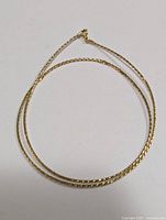 Top view of thin gold chain laid flat showing chain details and clasp.