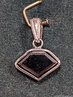 Close-up front view of the geometric black diamond pendant set in 14KT gold with detailed bail.