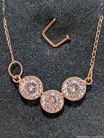 Close-up photo showing the 17-inch 10KT gold necklace with three round moissanite stones bezel-set horizontally. Chain and stones clearly visible.