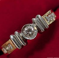 Front view of ring on red background showing center diamond and stepped gallery design