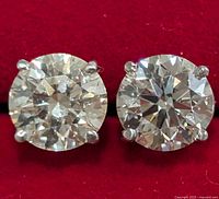 Front view of two round brilliant cut diamonds in four-prong white gold settings on red background