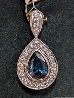 Close-up front image of the pendant showing pear-shaped blue lab diamond surrounded by round CZ stones and bail with CZ accents.