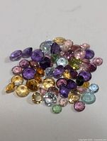 Close-up of assorted genuine multi gemstones in various colors and cuts placed on a flat surface.