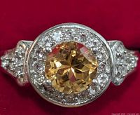 Close-up photo of round citrine center stone surrounded by white topaz set in sterling silver with split shank band.