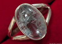 Close-up of silver ring with large oval clear gemstone showing internal inclusions and the band split design.