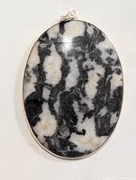 Close-up photo of an oval pendant with a black and white marbled gemstone in a silver bezel setting.
