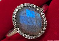 Close-up front view showing the oval labradorite and halo of small clear stones on a silver band.