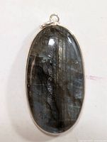 Front view of oval labradorite gemstone pendant in silver frame highlighting the stone's blue and grey sheen.