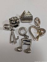 Clear close-up of all five silver Pandora-style beads arranged to show detail and design.