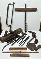 Full view of all antique and vintage hand tools including wood plane, saw, auger drill, pliers, folding rulers and iron tools