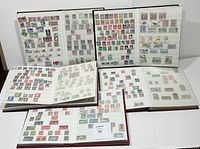 Overview of five stamp album books opened and displayed, showing variety of stamps on multiple pages.