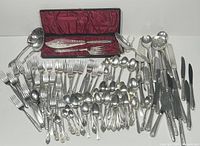 Photo showing full assortment of silverplate flatware laid out along with boxed fish server set with burgundy satin interior lining.