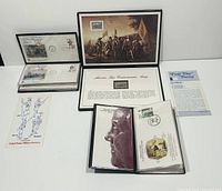 Display showing multiple commemorative stamp presentation folio cases containing first day covers and stamp collections.