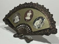 Front angled view of brass fan-shaped 3-photo frame showing ornate brass edges and vintage photos inside