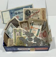Box filled with mixed foreign coins and banknotes in circulated condition.