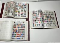Three stamp albums open to show various worldwide stamps on pages