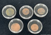 Top view of 5 Dutch VOC coins enclosed in clear protective plastic capsules on a black background.