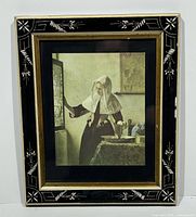 Framed print showing full image of Woman at the Casement by Jan Vermeer with ornate black and gold frame.