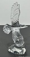Clear lead crystal eagle figurine in flight showing wing and feather details on a black background.