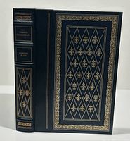 Front and spine cover of the book showing black cover with gold gilt decoration and text.