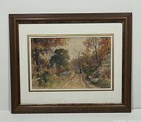 Framed watercolour landscape painting with autumn trees and a solitary figure walking along a dirt path.