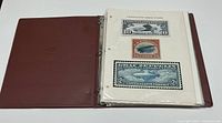 Open brown 3-ring binder with plastic sleeves displaying three airmail postage stamps of various denominations mounted on a white album page.