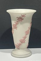 Full front view of the vintage Canada art pottery vase showing the white body with raised pink floral accents and its flared mouth and round base.