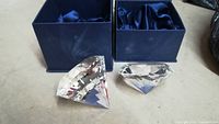 Both crystal diamond-shaped decor pieces displayed outside their blue boxes with satin interior.