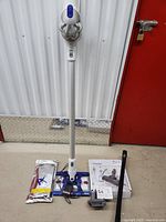 Full view of Dyson DC57 vacuum with charging dock, floor wipes pack, and other accessories