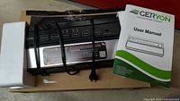Geryon vacuum sealer and user manual on a cardboard surface with protective foam on one side.